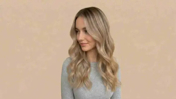 Kobieta z falowanymi włosami w odcieniu piaskowy blond, z subtelnymi refleksami.