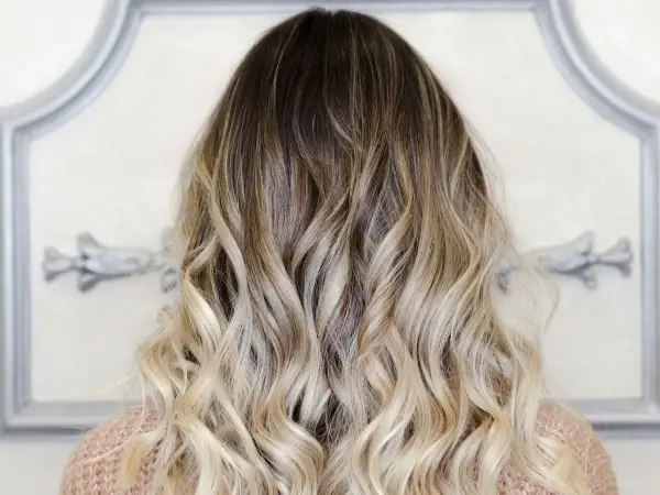 Piękne, falowane włosy z efektem ombre blond, przechodzące od ciemnego brązu do jasnego blondu.
